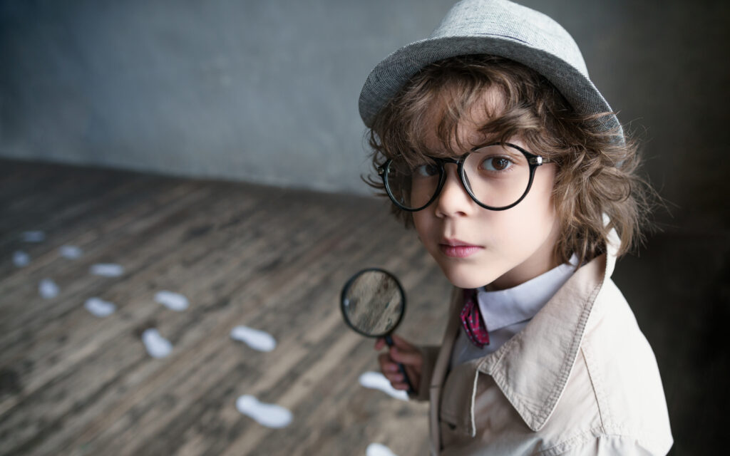 Boy holding a magnifying glass.