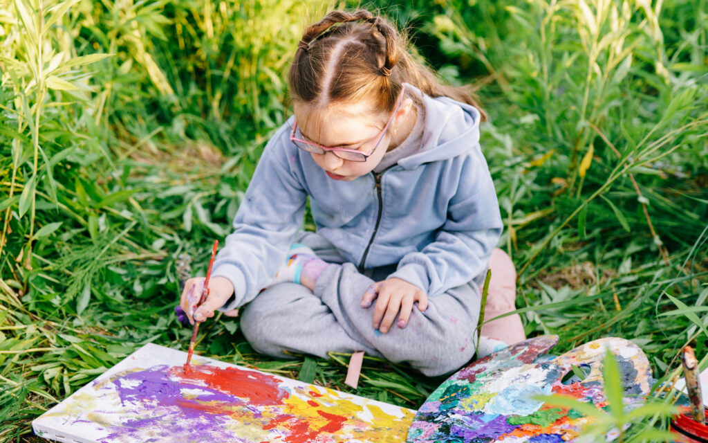 Girl painting in the grass.
