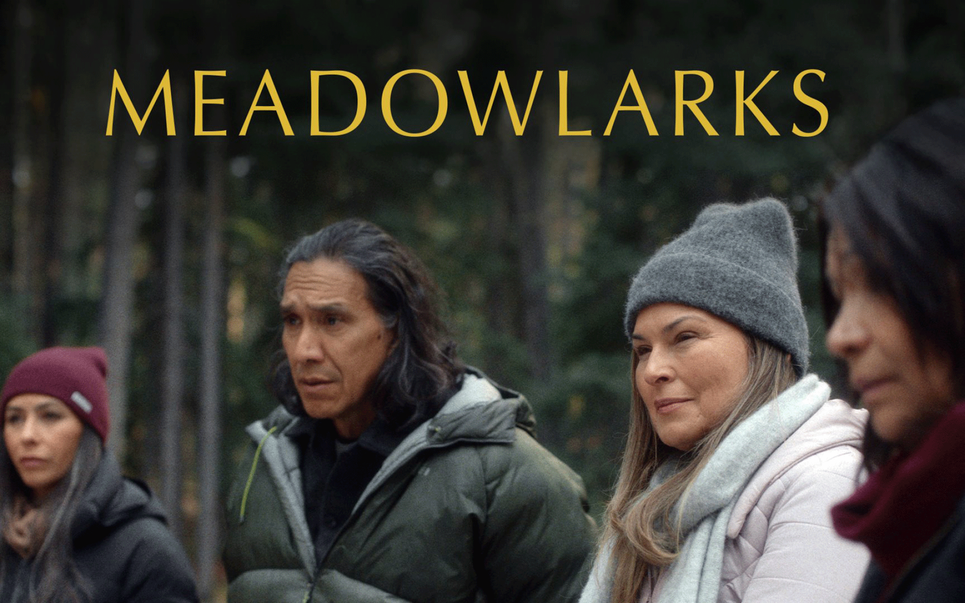 Four people standing together in winter coats and hats with the word Meadowlarks.