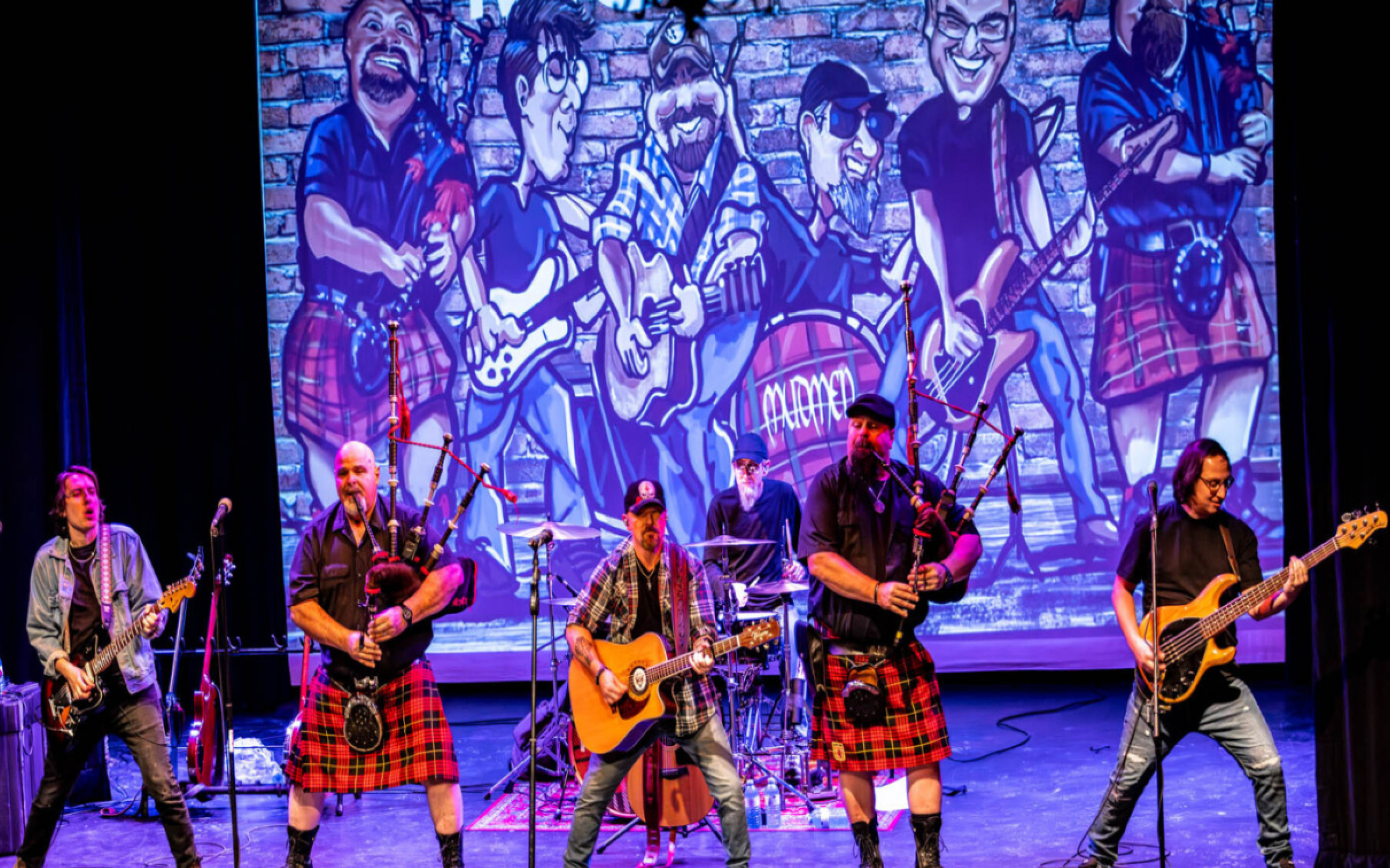 Men in quilts playing instruments on stage.